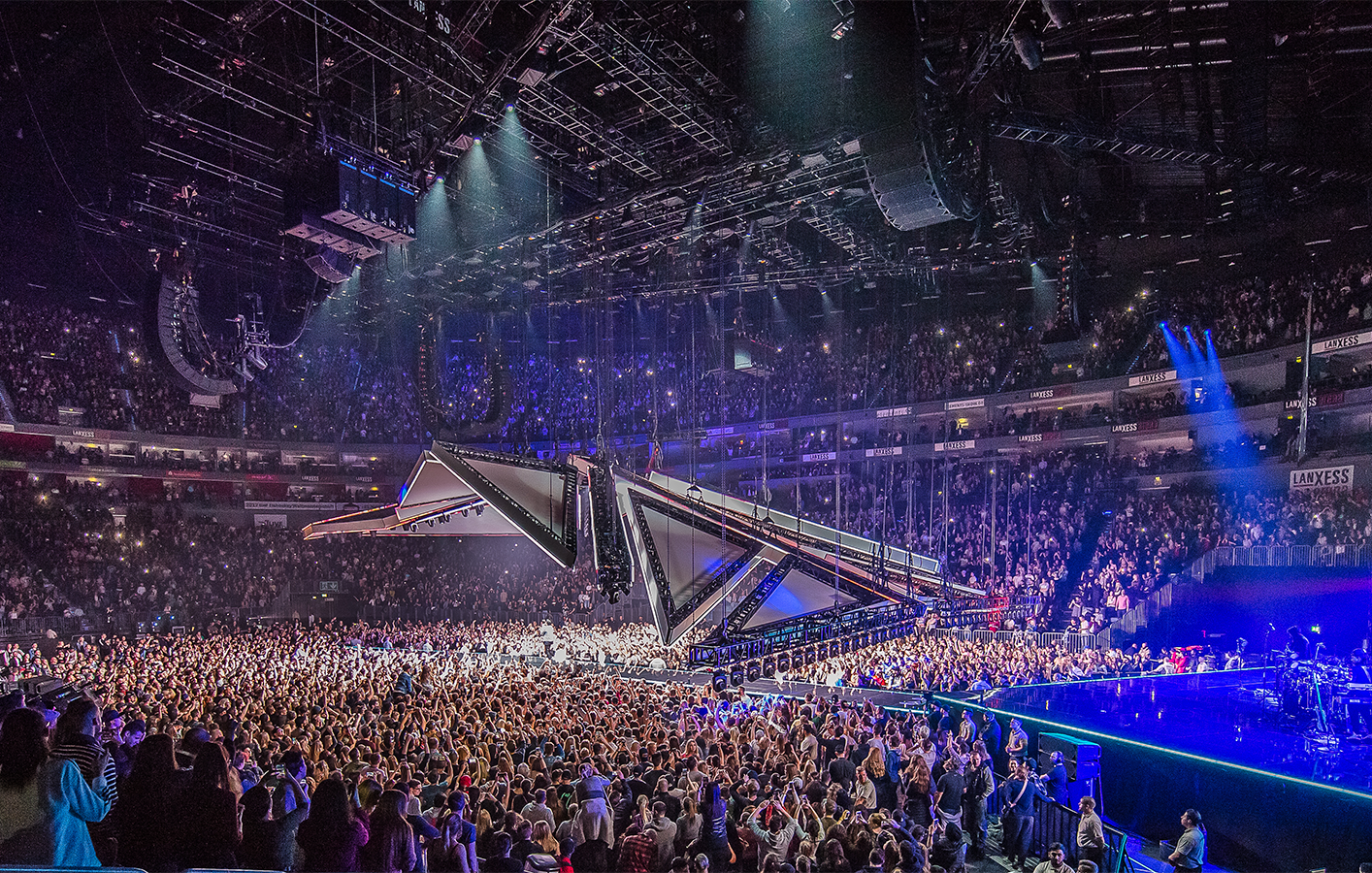 Large crowd in indoor arena cheering on the Weeknd