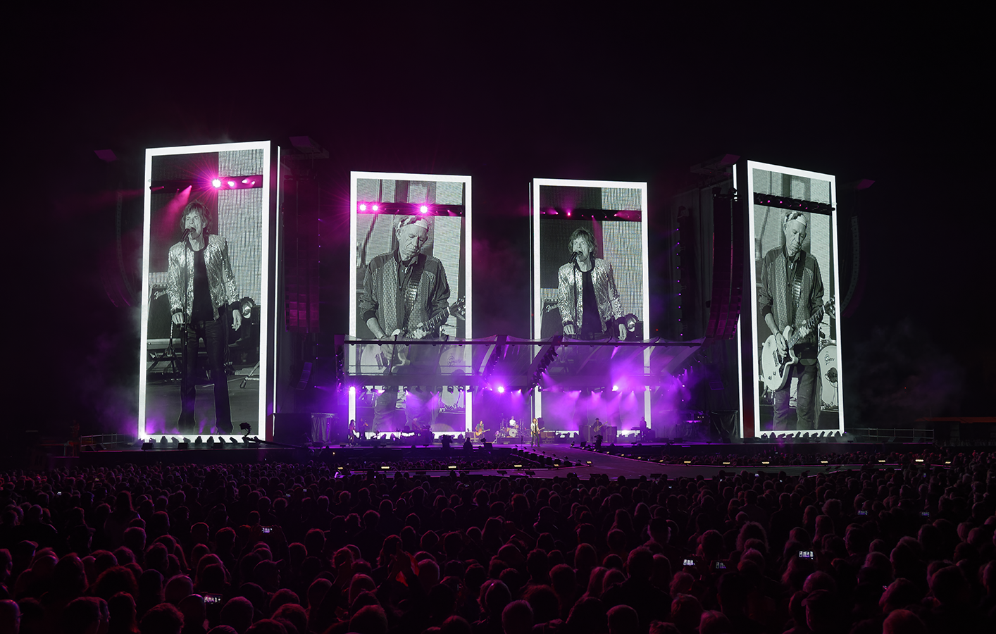 Portrait styled video displays show members of the Rolling Stones playing live