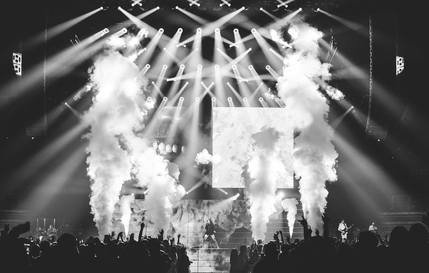 Halsey performs on stage surrounded by jets of smoke and lighting beaming out to crowd