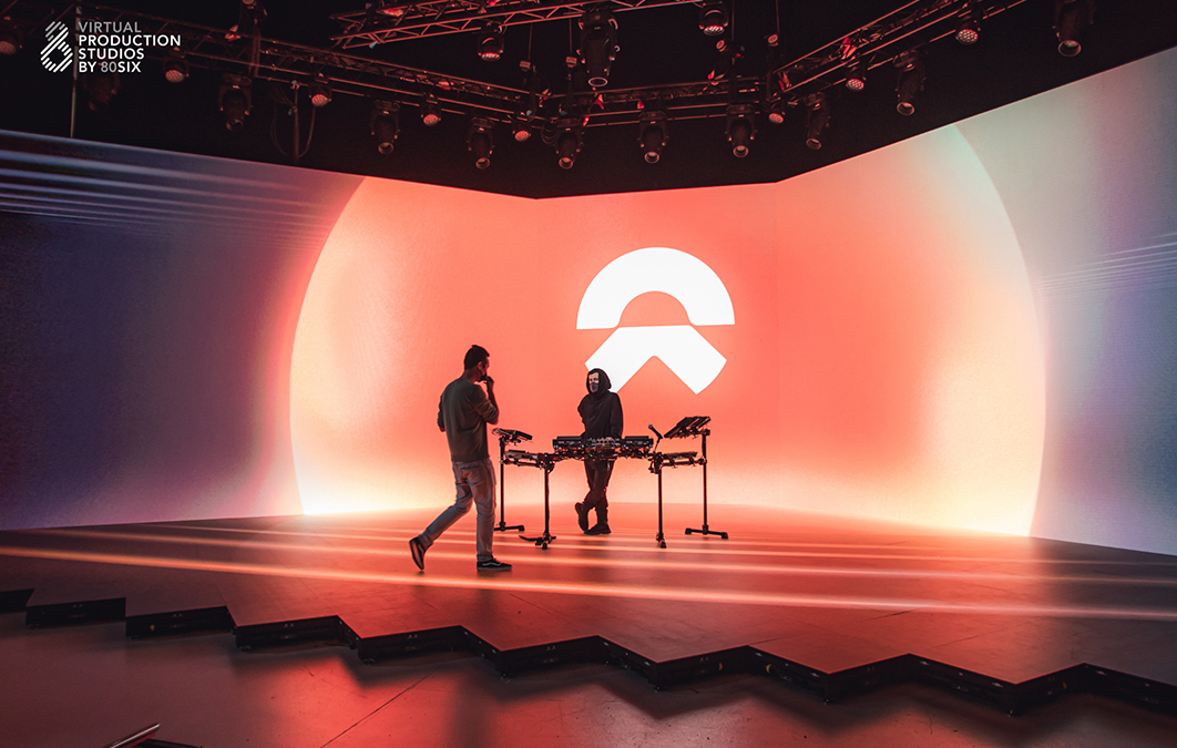 Musician stands on LED stage as he's joined by film crew member