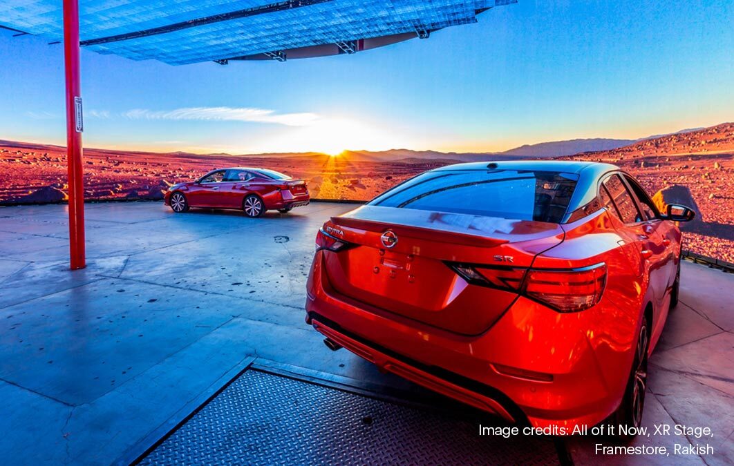 Two red Nissan cars on stage with desert scene background