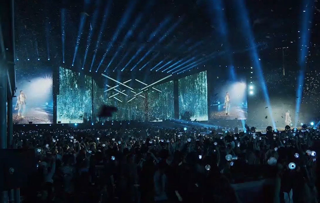 Crowd watching BTS's performance. LED screen displays rain effects