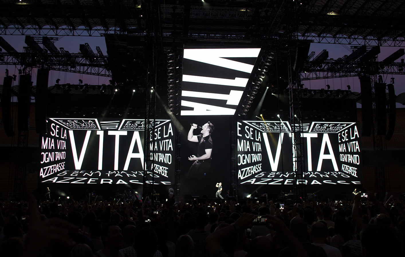 Tiziano Ferro singing on stage as big bold white letter display on multiple LED screens