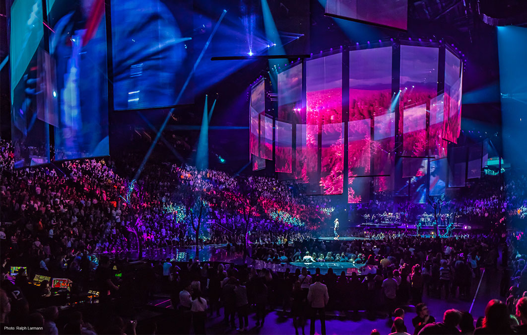 Crowd watching justin timberlake, with venue covered in blue, red and purple lighting