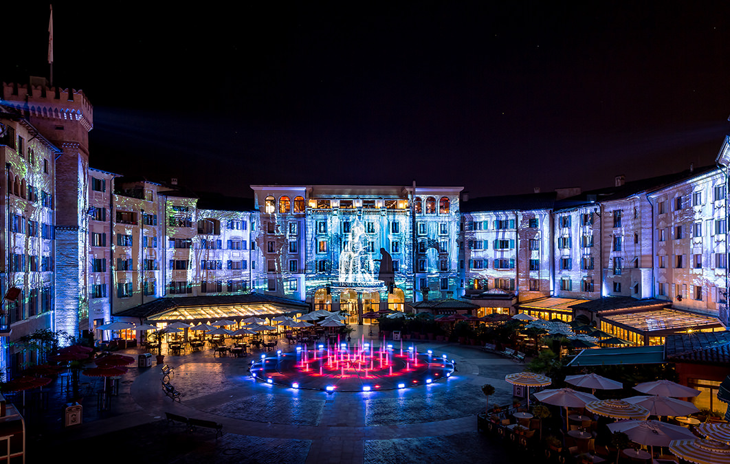 Man standing by water fountain projected across buildings in Europa Park