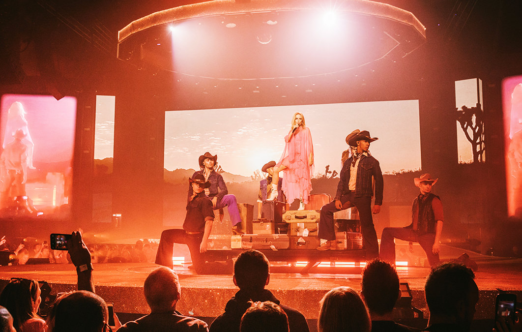Kylie Minogue performing on stage with an American cowboy themed set