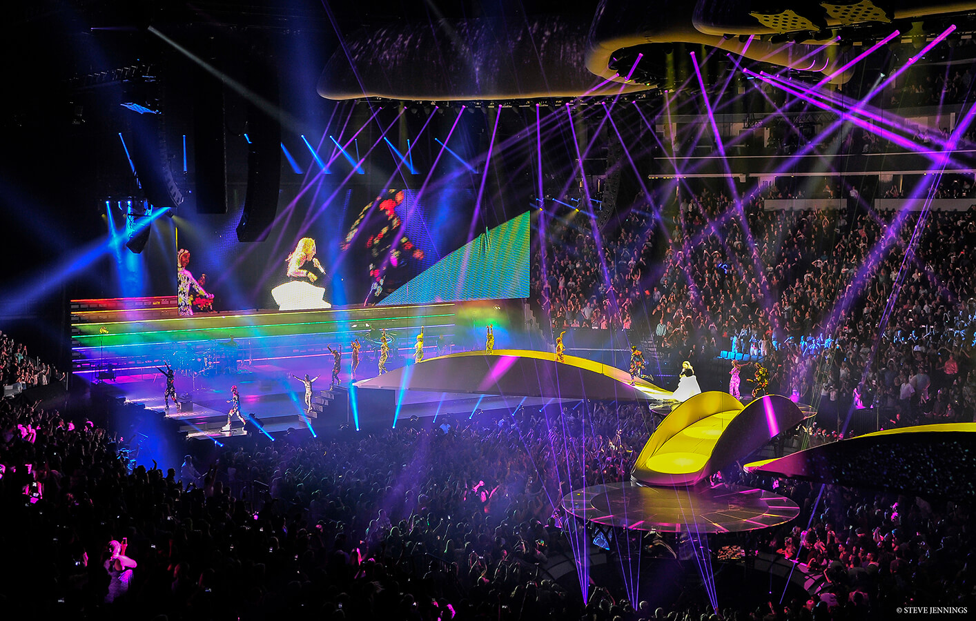 Lady Gaga performs across bridge feature at arena venue with various dancers