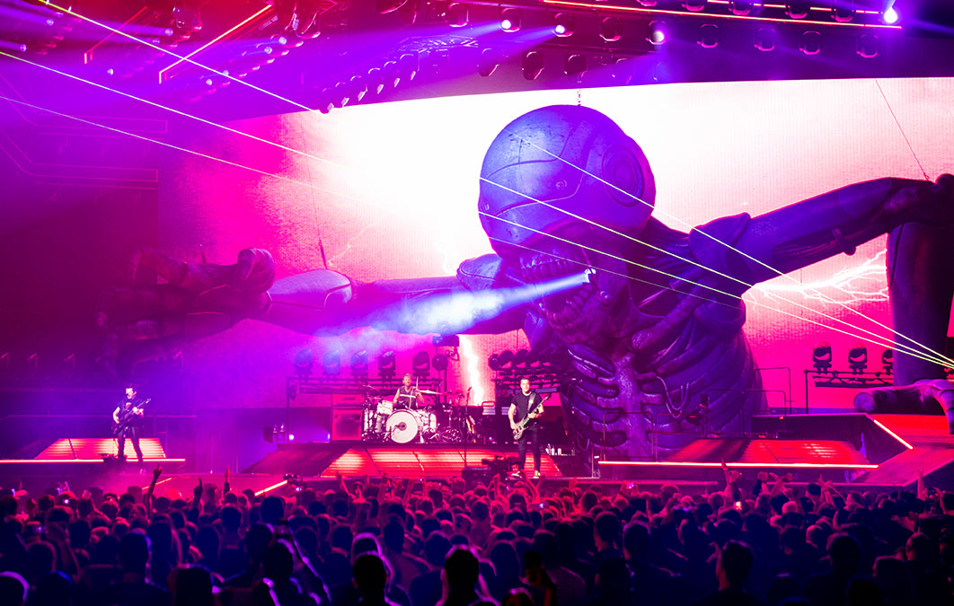 Muse playing live on stage with massive robot model reaching out to crowd