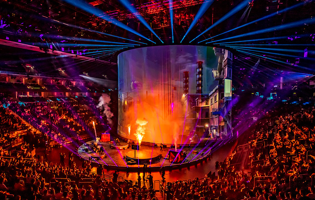 Large crowd in arena watching rock band play on stage