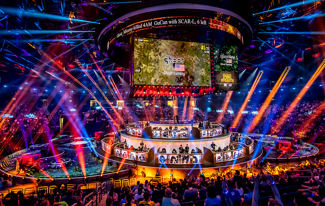 Stage set-up for eSports event featuring multiple screens showing in game footage and players