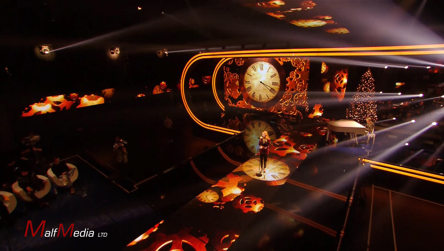 Woman signs live on stage with clocks featured on various video displays