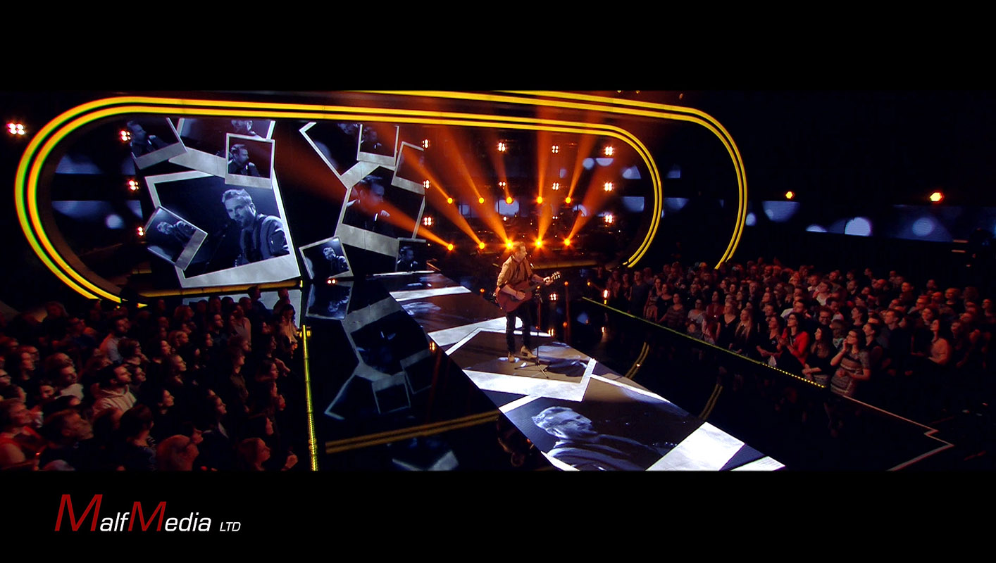 Man playing acoustic guitar on stage with Polaroid visual effect used on various display screens