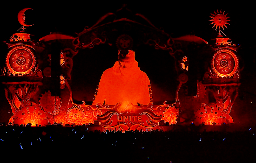 A Dj seen on a large video screen with red lighting and effects