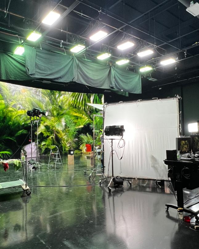 TRG Multimedia production crew working on set in front of an LED wall displaying a digital environment.
