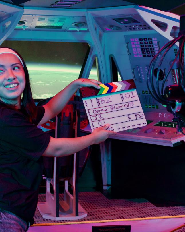 Student holding a slate in front of the 3D printed spaceship on the LED Volume