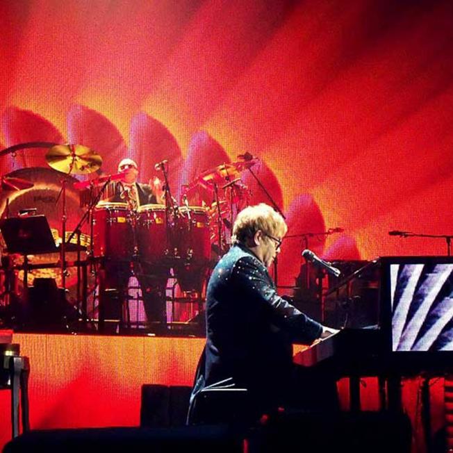 Elton John playing piano on stage
