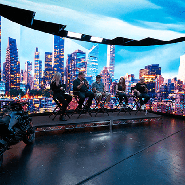 panel with 5 speakers in front of led stage showing city scape