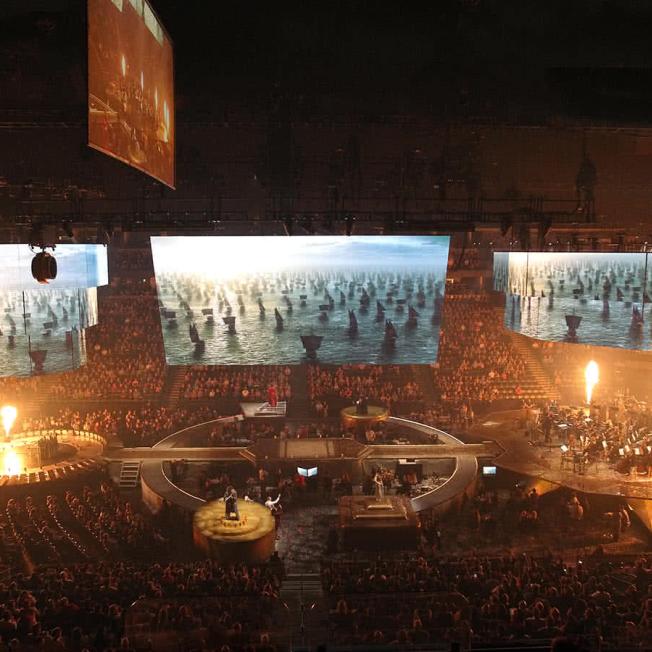 Orchestra performs on stage whilst LED displays shows videos game of thrones