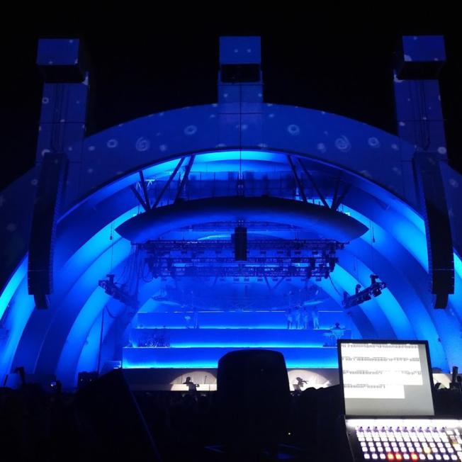 Stage lit with blue lighting seen from sound desk
