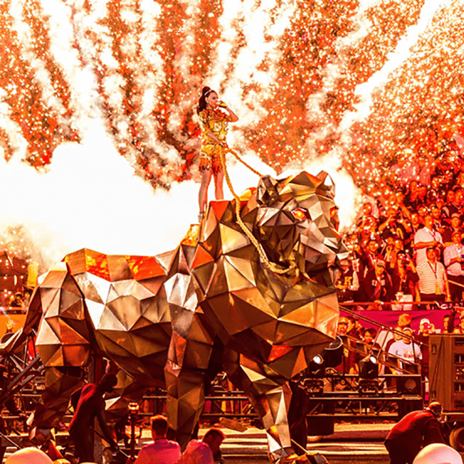 Katy Perry singing while standing on large metallic lion