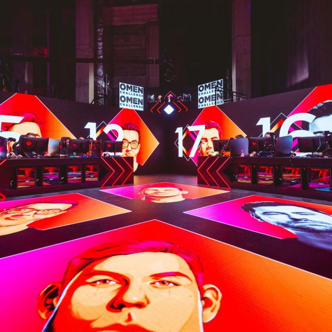 stage design for Omen esports event featuring players faces displayed on floor screens