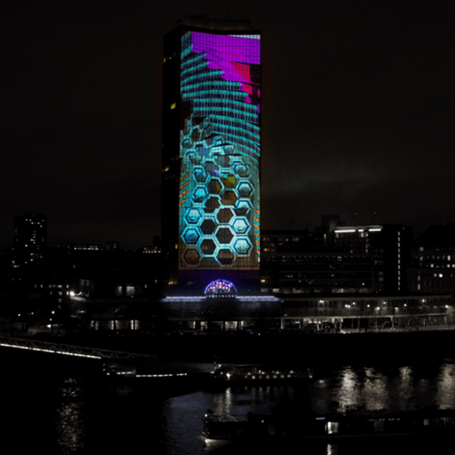 Millbank Tower in London lit up with blue and purple lighting