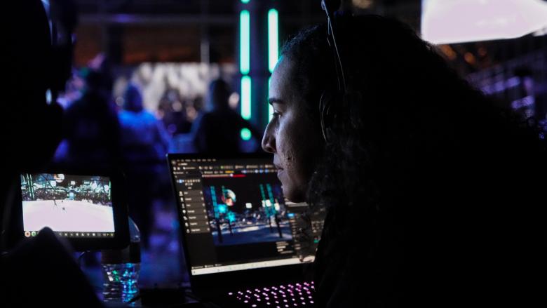 An artist monitors a real-time 3D environment on a laptop during a live virtual production shoot.