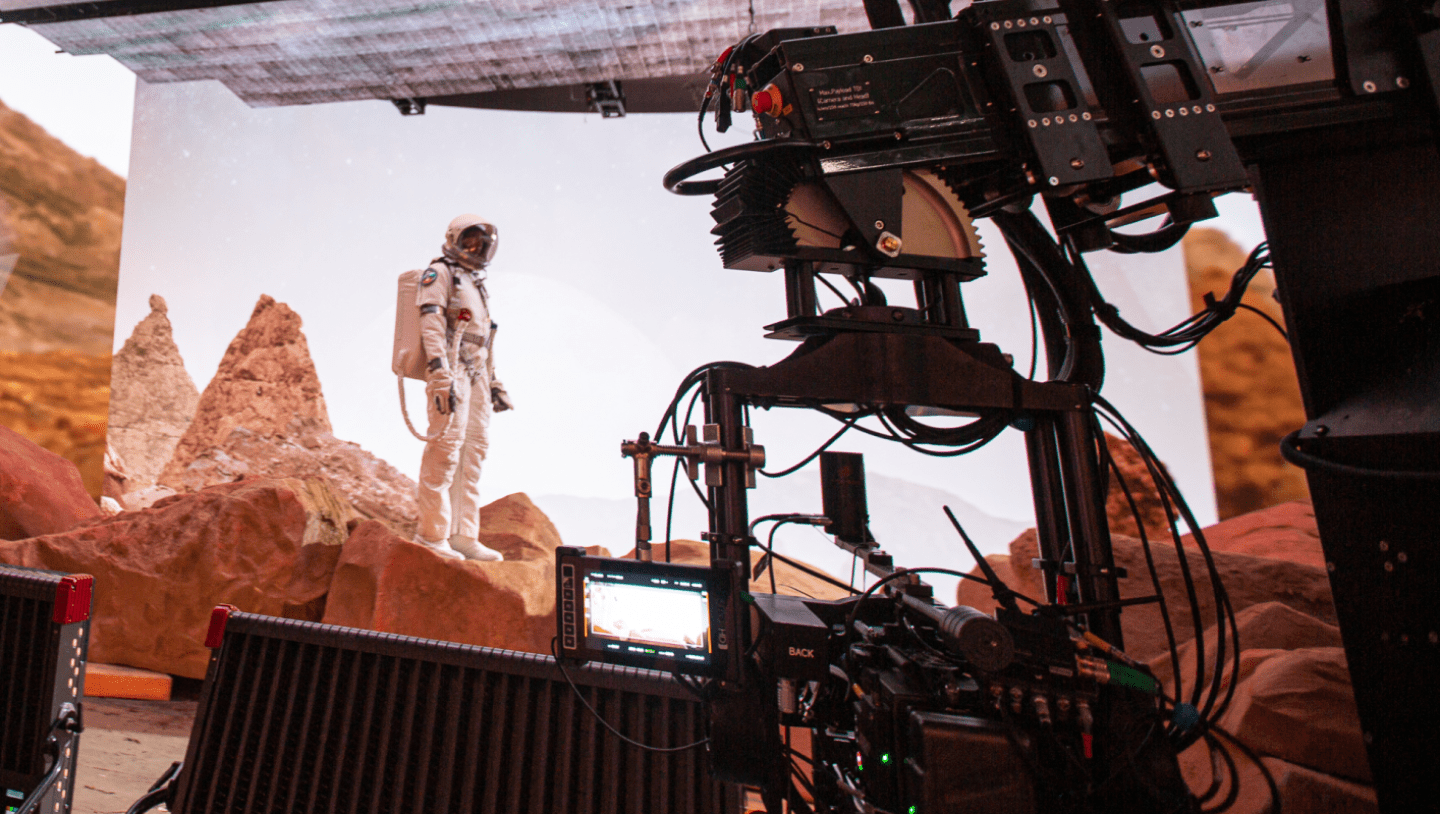 Camera films man in space suit on stage
