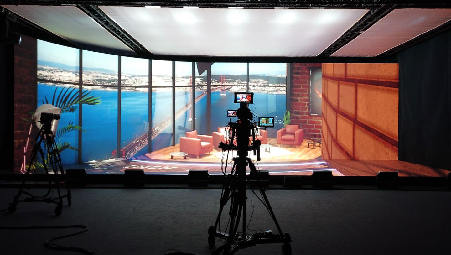 Camera positioned in front of LED stage showing casual office space