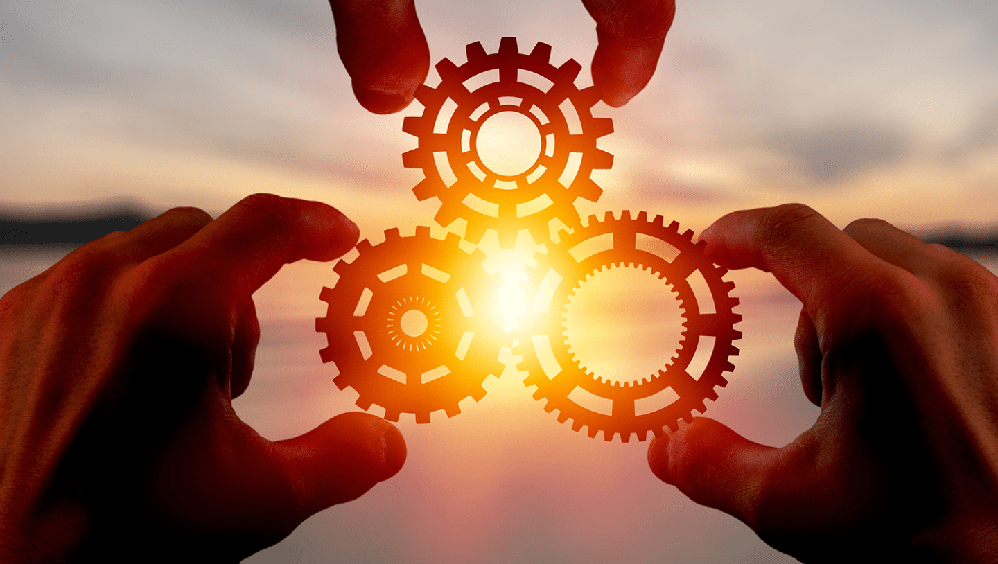three hands holding cogs