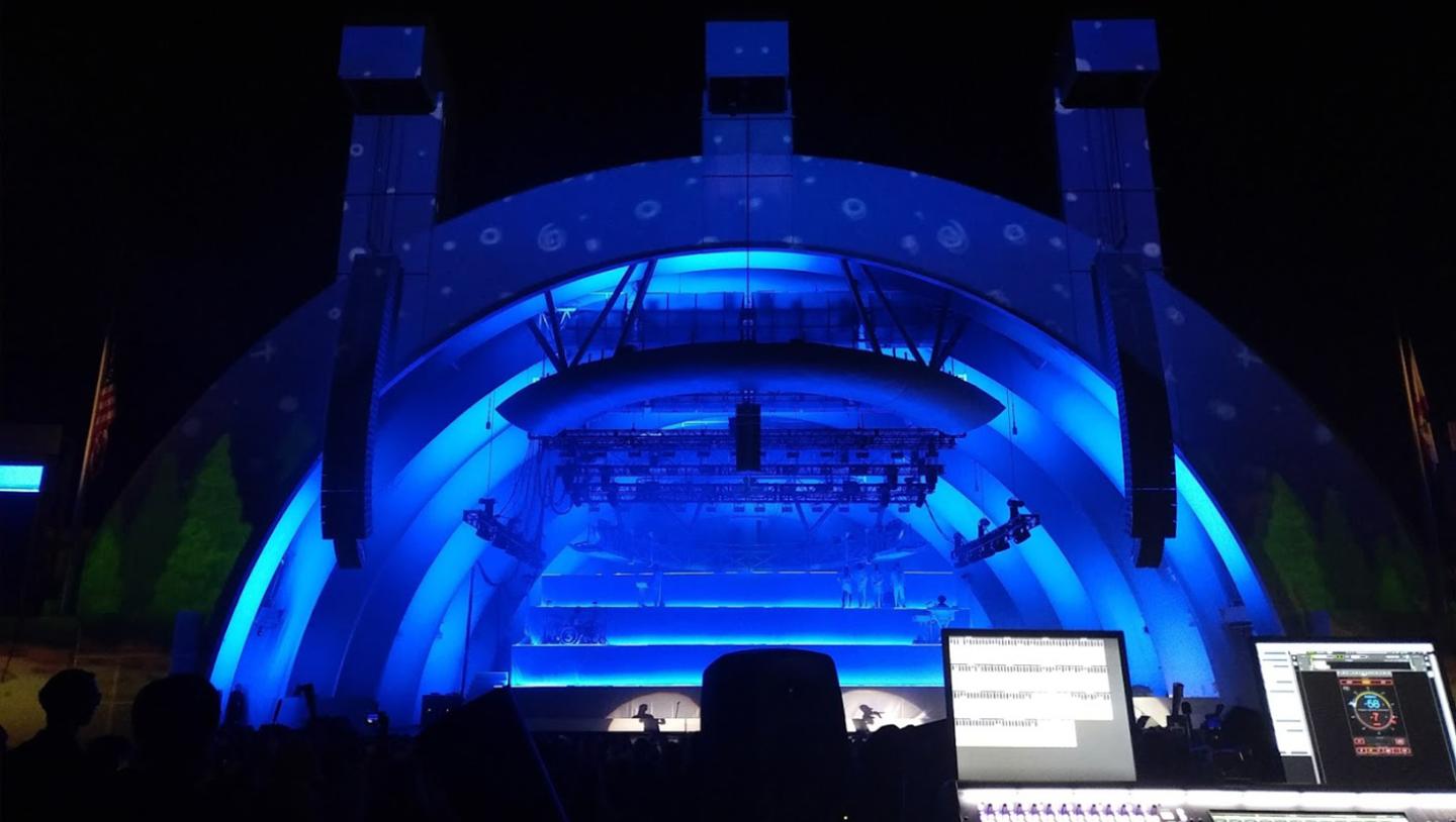 Stage lit with blue lighting seen from sound desk