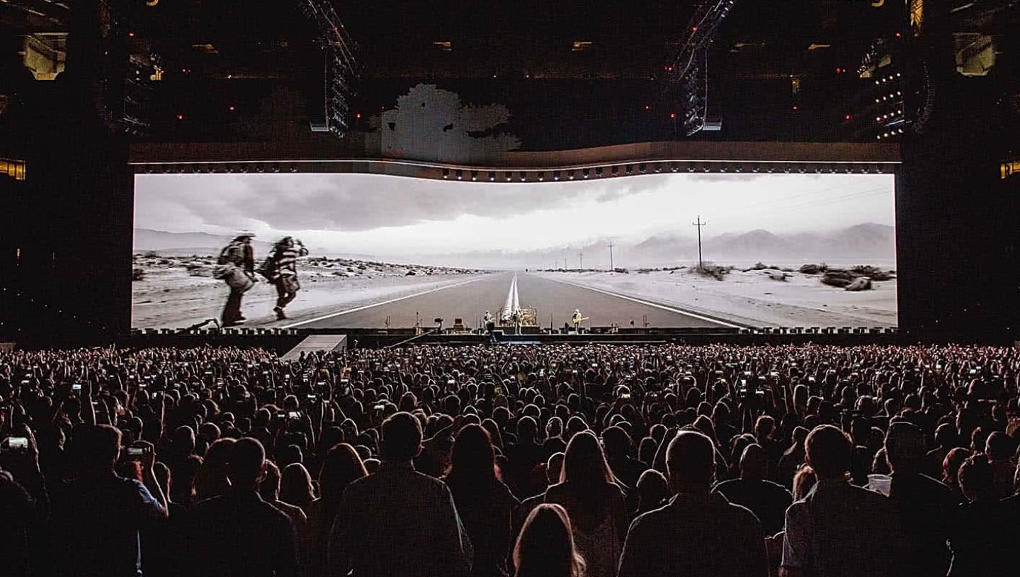 Crowd watching u2 play in front of large LED Display
