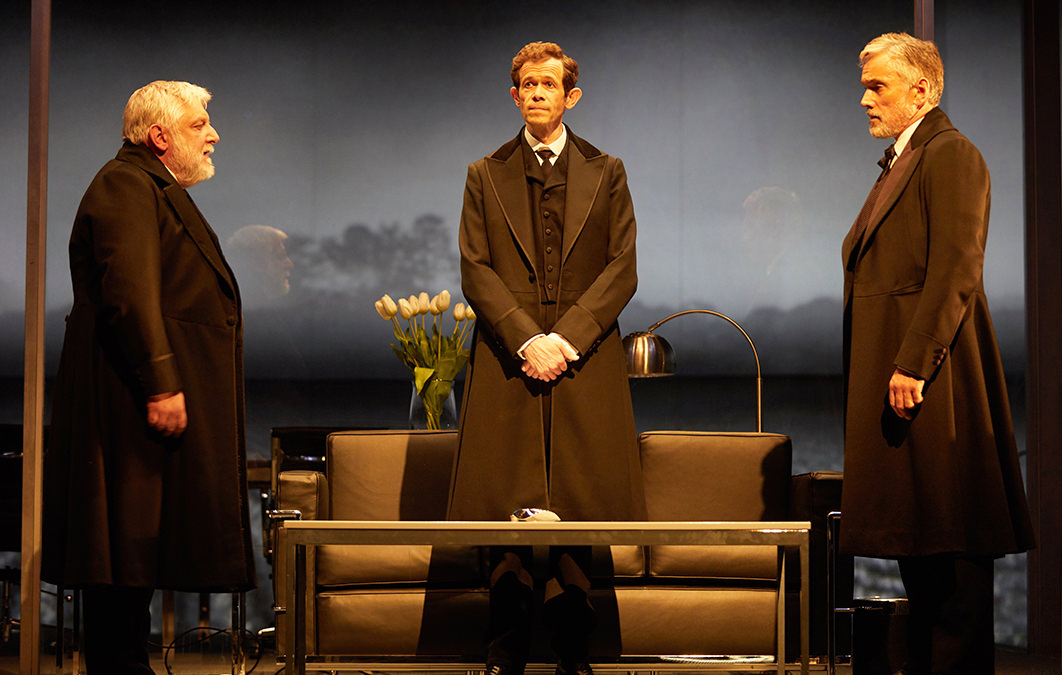 three actors on stage in formalwear for The Lehman Trilogy stage production