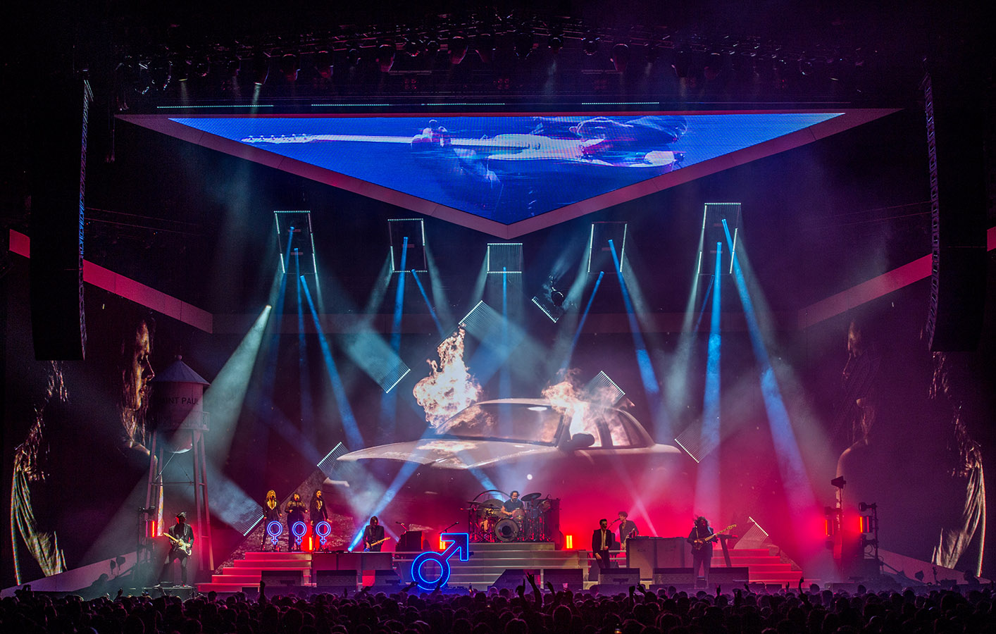The Killers playing on stage with visuals of car on fire displayed on screen